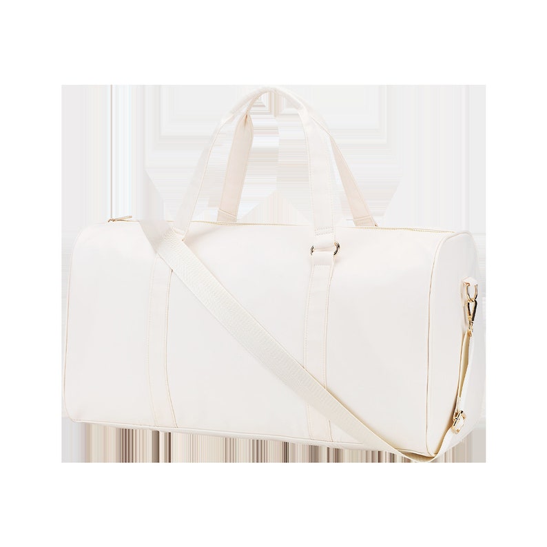 May include: A white canvas duffel bag with a long shoulder strap and gold accents.