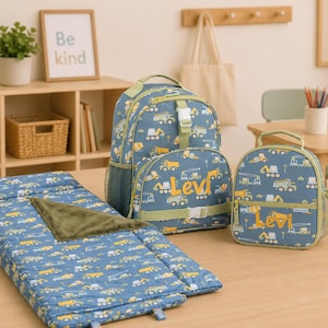 May include: A blue backpack, lunch bag, and sleeping mat set with a construction vehicle pattern. The backpack and lunch bag have the name "Levi" printed on them. The sleeping mat has a green blanket.