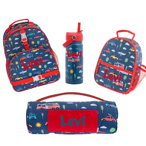 Könnte beinhalten: Ein Set aus marineblauem Rucksack, Lunchpaket, Wasserflasche und gerollter Decke. Jeder Artikel hat eine rote Umrandung und den Namen "Levi" in Rot. Das Set hat ein Muster aus Autos, Flugzeugen und Bäumen.