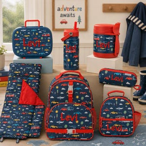 May include: A collection of navy blue travel accessories with a car and travel-themed pattern. Includes a lunchbox, backpack, water bottle, sleeping bag, and pencil case. Each item is personalized with the name "Levi" in red.