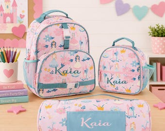 May include: A pink backpack, lunch bag, and pencil case set with a princess theme. The bags feature a floral and princess pattern with the name "Kaia" in a light blue color. The backpack has a main compartment, side pockets, and adjustable straps.
