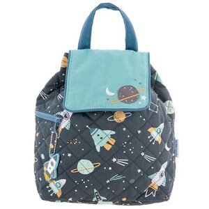 May include: A space-themed quilted backpack. The dark grey bag features a pattern of rockets, planets, and stars in blue, yellow, and white. It has a teal flap and handle, and a small rocket-shaped zip pull. The bag is approximately 25 cm high.