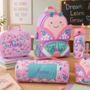 May include: A collection of butterfly-themed school supplies including a backpack, a lunch box, a water bottle, a nap mat, and a small snack bag. Each item features a pink, purple, and teal color palette with floral patterns and the name Anna.