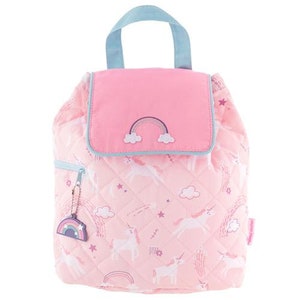 May include: Pink quilted backpack with a unicorn and rainbow pattern. Features a pink flap with a rainbow applique and a light blue handle. Includes a rainbow charm on the zipper.