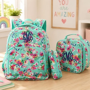 May include: A matching school set featuring a backpack, lunch bag, and pencil case. The set has a teal background with a floral pattern in pink, yellow, and red. Each piece has a monogram in navy blue.