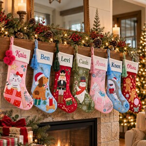 Peut inclure: Sept chaussettes de Noël personnalisées suspendues en rangée, chacune avec un revers blanc brodé d'un prénom : Kaia, Ben, Levi, Cash, Anna, Knox et Olivia. Les chaussettes présentent des motifs festifs incluant un chat, un chien, un casse-noisette, un bonhomme de neige, un cheval, un requin et des bonshommes en pain d'épice.