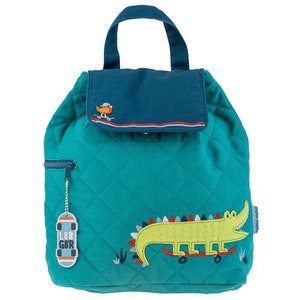 May include: A teal blue quilted backpack with a flap top closure. The backpack features a green alligator with red and white accents riding a skateboard. The backpack has a small pocket on the front with a bird graphic and the text "L&B GBR".
