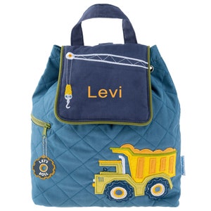 Peut inclure: Sac &agrave; dos matelass&eacute; bleu avec un rabat bleu marine portant le nom "Levi" en orange. Le rabat pr&eacute;sente un motif de grue. Un camion benne jaune et vert est sur le devant. Le sac a une fermeture &eacute;clair et un charme "Let's Roll".