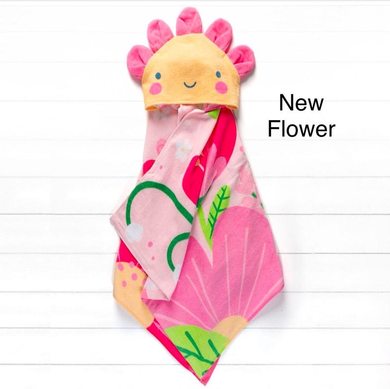 May include: Pink hooded towel with a floral design and a yellow flower-shaped hood with a smiling face. The text "New Flower" is written in black on a white background.