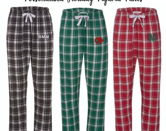 Könnte beinhalten: Drei Paar karierte Schlafanzug-Hosen mit verschiedenen karierten Mustern. Die Hosen sind schwarz-weiß, grün-weiß und rot-weiß. Jedes Paar hat ein Monogramm auf dem linken Bein.