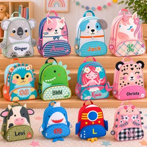 May include: A collection of colorful children's backpacks with various animal and character designs. The backpacks feature koala, cat, dog, unicorn, hedgehog, dinosaur, mermaid, leopard, cow, shark, rocket, and floral patterns. Each backpack has a name printed on it.