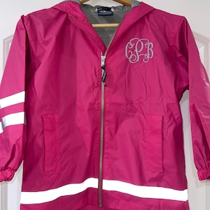 May include: A pink hooded raincoat with reflective stripes and a monogrammed "C.S.B." on the front.