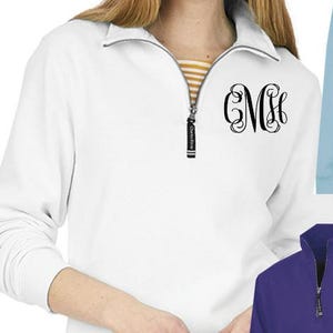 May include: White quarter-zip sweatshirt with a black monogram "CMH" on the chest. The sweatshirt has a zipper with a black pull tab. The model is wearing blue jeans.