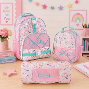Könnte beinhalten: Rosa-blaue Rucksack-, Lunchbox- und Reisetaschen-Set mit Einhorn-Motiven. Jede Tasche trägt den Namen "Christa" und türkisfarbene Akzente. Geeignet für Schule oder Reisen.