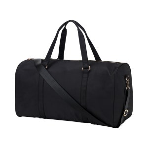 May include: A black duffel bag with a long shoulder strap and two top handles. The bag has gold-colored hardware.