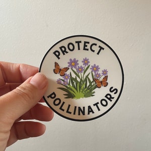 Könnte beinhalten: Ein runder Aufkleber mit weißem Hintergrund und schwarzem Rand. Der Aufkleber zeigt eine Grafik mit lila Blumen und zwei orangefarbenen Schmetterlingen. Der Text "PROTECT POLLINATORS" ist in Schwarz um den Rand des Aufklebers geschrieben.