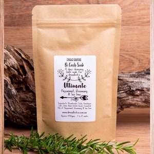 May include: A brown paper bag with a white label that reads "Dread Empire Bi Carb Soak Ultimate Peppermint, Rosemary & Tea Tree". The label also includes the ingredients and website address.