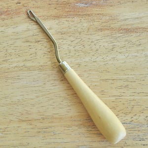 May include: A wooden crochet hook with a metal hook and a wooden handle.