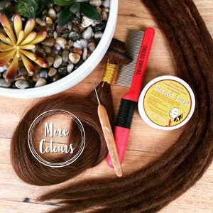 May include: Brown dreadlocks hair extensions with a wooden dreadlock tool, a red comb labeled "Dread Empire", and a container of "Dread Dust" hair product.