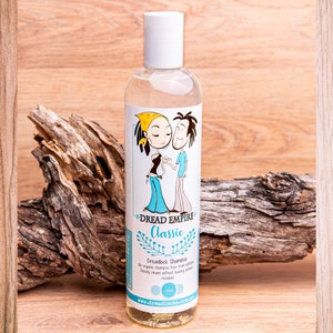 May include: A clear plastic bottle of Dread Empire Classic Dreadlock Shampoo. The bottle has a white cap and a cartoon illustration of a couple with dreadlocks. The text on the bottle reads "Dread Empire Classic Dreadlock Shampoo An organic, shampoo free from sulfates Deeply cleans without leaving any residue www.dreadlocks.com.au dreadlocks"