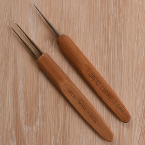 Peut inclure: Deux crochets en bois pour le crochet avec des pointes métalliques. Le crochet de gauche est étiqueté "Dread Empire - 0,5 mm" et le crochet de droite est étiqueté "Dread Empire - 0,6 mm".