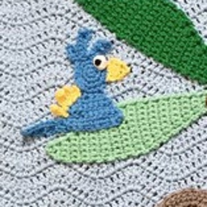 May include: A blue bird with yellow accents is crocheted and sitting on a green leaf. The bird has large black eyes and a small yellow beak. The leaf is crocheted and has a light green color.