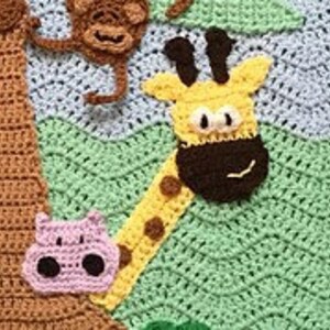 May include: A crocheted baby blanket with a green, blue, and yellow background. The blanket features a brown tree with a yellow giraffe, a brown monkey, and a pink hippopotamus.