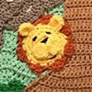 May include: A crocheted lion face applique in yellow, orange, and brown. The lion has a friendly expression with a small black nose and two black eyes.
