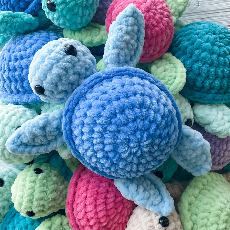 May include: A group of crocheted turtle toys in various colors, including blue, green, pink, and white. The turtles are made with a soft, fuzzy yarn and have detailed features, such as eyes and shells.