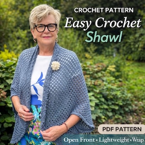 Puede incluir: Una mujer lleva un chal de ganchillo azul con un frente abierto y un diseño ligero. El chal está asegurado con un broche de flores color crema. La imagen incluye el texto "Easy Crochet Shawl" y "PDF Pattern".