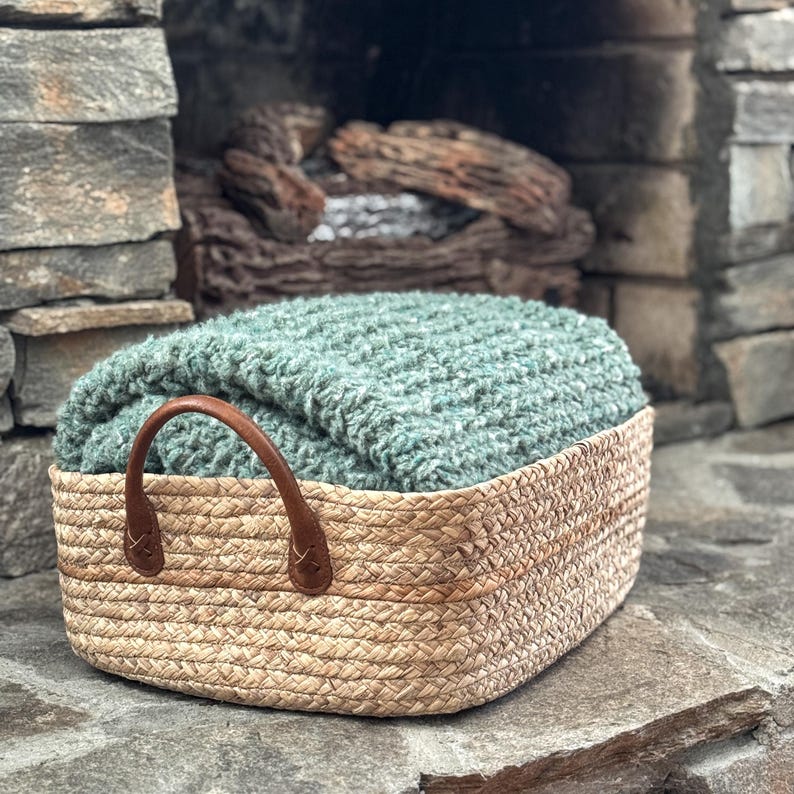 Chunky crochet blanket in soft, thick yarn showcasing cozy, textured stitches perfect for beginners. Draped gently over a sofa, ideal size for home decor accents. PDF crochet pattern with video tips included for easy crafting