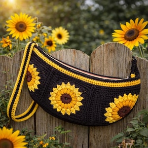 Puede incluir: Bolso de hombro de ganchillo negro con tres grandes aplicaciones de girasoles amarillos y marrones. El bolso tiene una correa amarilla y negra y una cremallera amarilla. El bolso se muestra en una valla de madera con girasoles en el fondo.