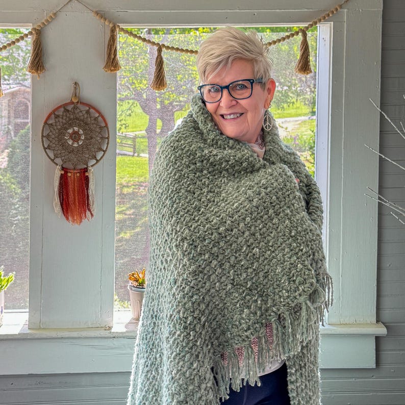 Chunky crochet blanket in soft, thick yarn showcasing cozy, textured stitches perfect for beginners. Draped gently over a sofa, ideal size for home decor accents. PDF crochet pattern with video tips included for easy crafting