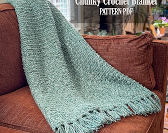 Puede incluir: Una manta de ganchillo grueso con un acabado de hilo verde salvia texturizado y detalles de flecos en el borde inferior. La imagen incluye el texto superpuesto Chunky Crochet Blanket PATTERN PDF, indicando que es un documento digital.