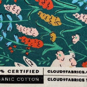 May include: Teal fabric with a floral pattern featuring pink, white, orange, and blue flowers. The fabric has a label that reads "100% Certified Organic Cotton" and "Cloud9Fabrics.com".