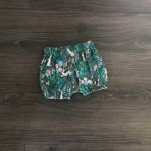 May include: Green and white patterned baby bloomers with a floral and bunny design.