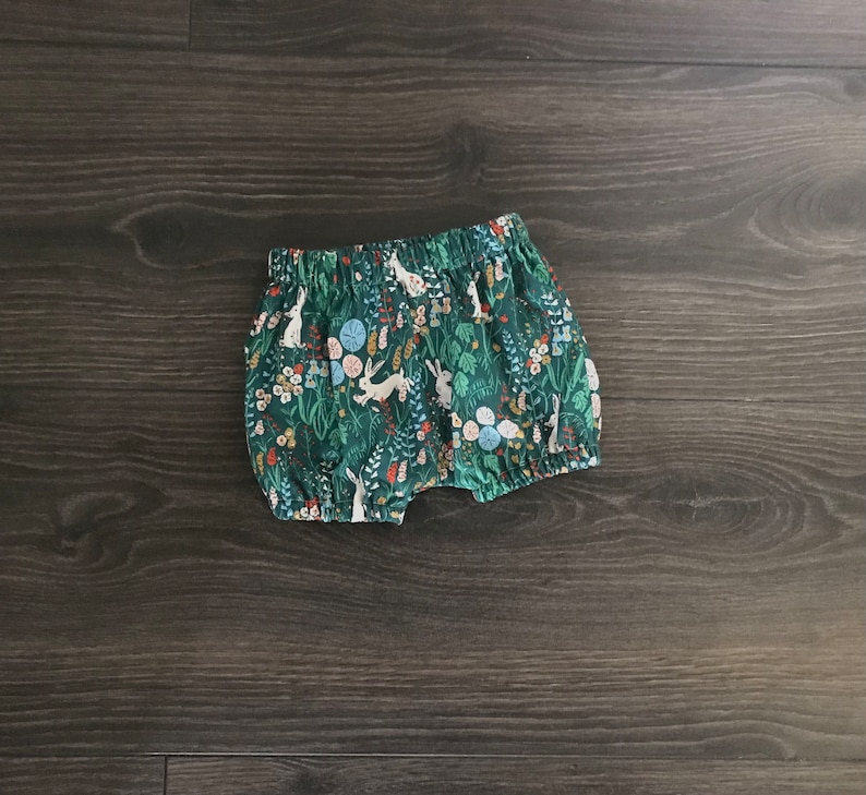May include: Green and white patterned baby bloomers with a floral and bunny design.