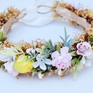 May include: A floral crown with pink, white, and yellow flowers, green leaves, and a gold base.