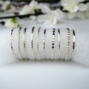 May include: A set of ten silver stacking rings with different textures, including a plain band, a beaded band, and a twisted band.