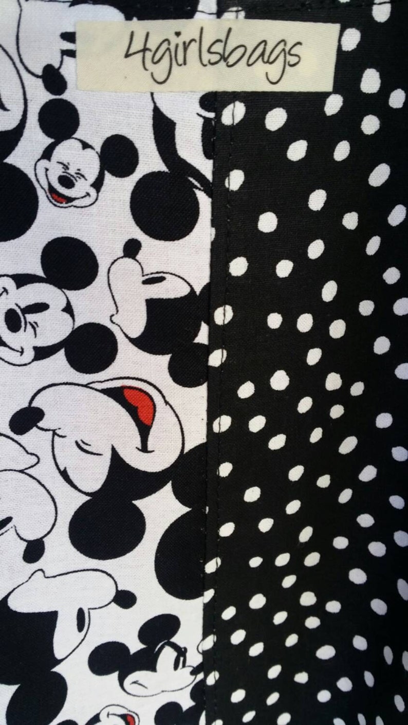 May include: Close-up of fabric with a split design. One side features a white background with black Mickey Mouse faces. The other side has a black background with white polka dots. The text "4girlsbags" is on a small label.