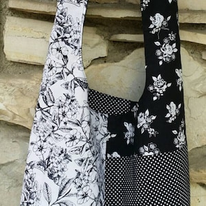 May include: A black and white floral and polka dot shoulder bag. The bag features a patchwork design with a white floral print on one side and a black floral print and polka dots on the other. The strap is also black and white floral.