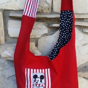 May include: A red shoulder bag with a Mickey Mouse and Minnie Mouse design. The bag features a red body, a white and red striped strap, and a black and white polka dot lining. The bag has a rectangular patch with Mickey and Minnie.