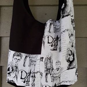 May include: Black and white tote bag with a Harry Potter theme. The bag features illustrations of Harry Potter, Ron Weasley, Hermione Granger, and other characters from the books. The bag also includes text from the books, such as "Harry Potter's" and "Dumbledore's Army".