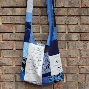 Puede incluir: Bolso de hombro patchwork azul con una correa larga. El bolso está hecho de varias telas, incluyendo mezclilla y estampados florales. El texto en el bolso incluye las frases "Porque de tal manera amó Dios al mundo" y "Confía en el Señor" con un corazón.