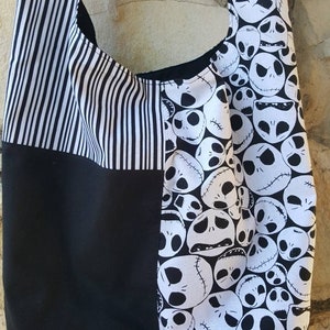 K&ouml;nnte beinhalten: Schwarze und wei&szlig;e gestreifte Stofftasche mit einem schwarzen und wei&szlig;en Jack Skellington-Druck auf einer Seite.
