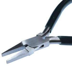 May include: Close-up of a pair of silver-toned pliers with black and green handles. The pliers have a flat, pointed jaw.