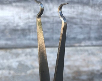 May include: A pair of silver-toned tweezers with curved tips. The tweezers are designed for precision work, such as picking up small objects or applying adhesives.