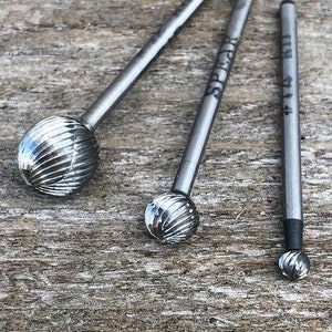 May include: Three silver metal rotary burrs with different sizes. The burrs have a round shape with a grooved texture. The burrs are labeled with the numbers "#11", "#12", and "#13".