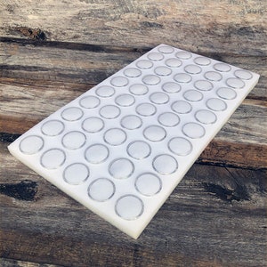 May include: White foam board with 60 round, silver-rimmed, empty containers for storing small items.