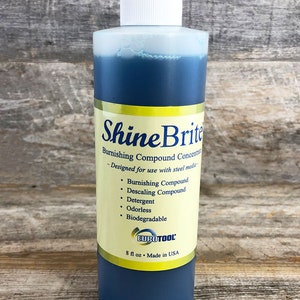 May include: A blue plastic bottle labeled "Shine Brite Burnishing Compound Concentrate" with the text "Designed for use with steel media" and a list of features: Burnishing Compound, Descaling Compound, Detergent, Odorless, Biodegradable. The bottle also has a yellow label with the text "EUROTOOL" and "8 fl oz Made in USA".